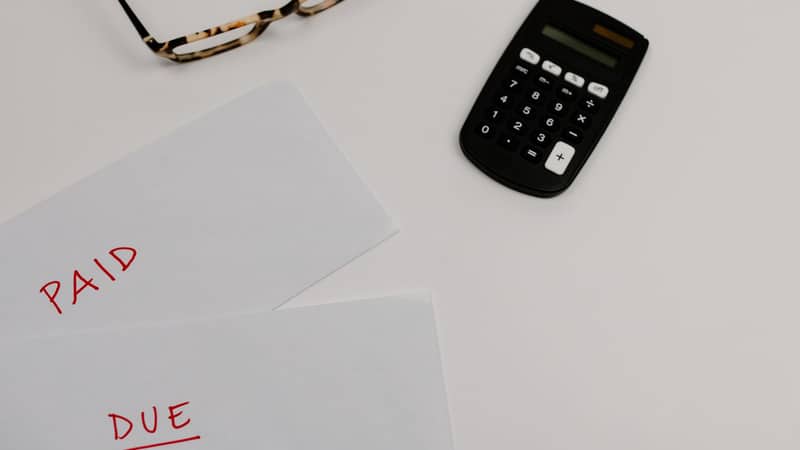 Sąskaitos su užrašais „Paid“ ir „Due“ šalia skaičiuotuvo